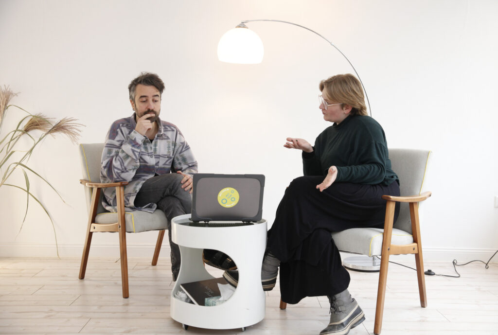 Zwei Menschen sitzen vor einem Laptop und überlegen